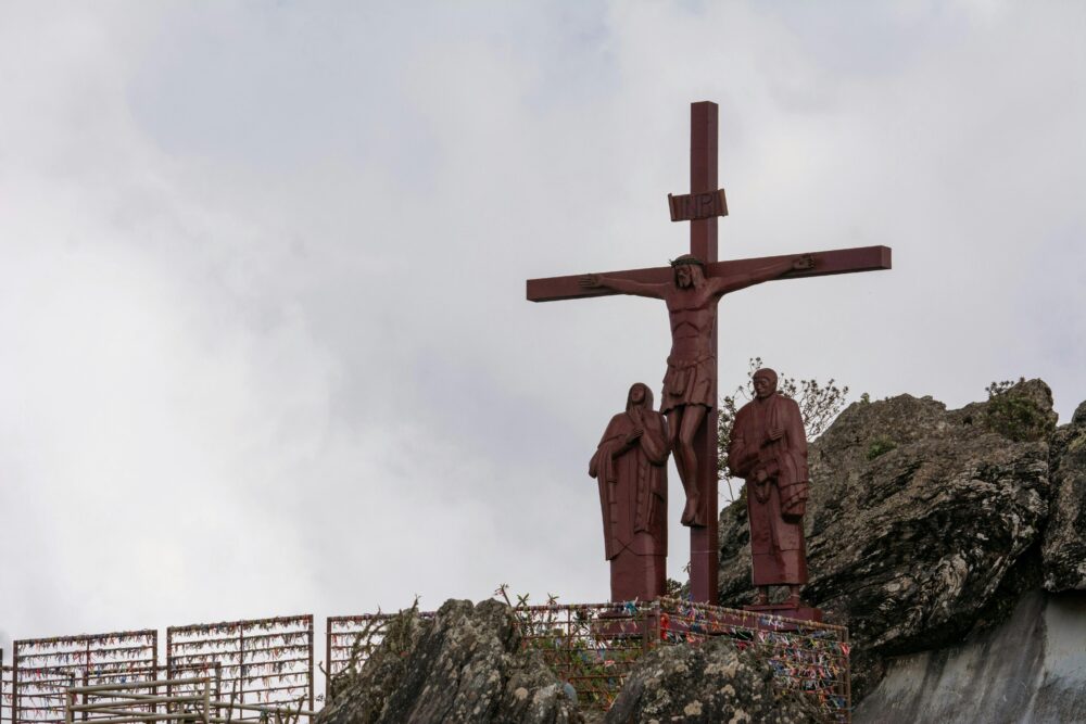 山頂的十字架和宗教雕像,在陰雲密布的天空映襯下,象徵著信仰和精神。