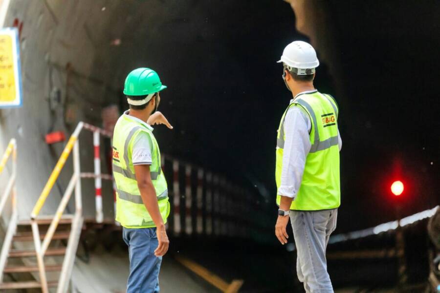 兩名建築工人正在檢查隧道入口，這凸顯了基礎設施項目中的安全和團隊合作的重要性。