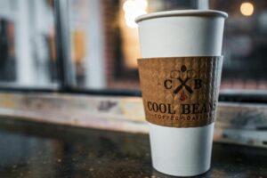 窗邊咖啡桌面托盤上掛著一個印有品牌標誌的咖啡杯，完美營造出溫馨的咖啡店氛圍。