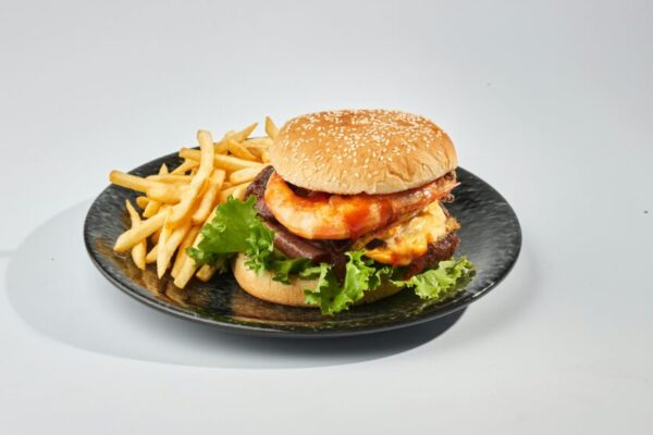 美味的起司漢堡，配上生菜、番茄和薯條，盛放在黑色托盤裡。
