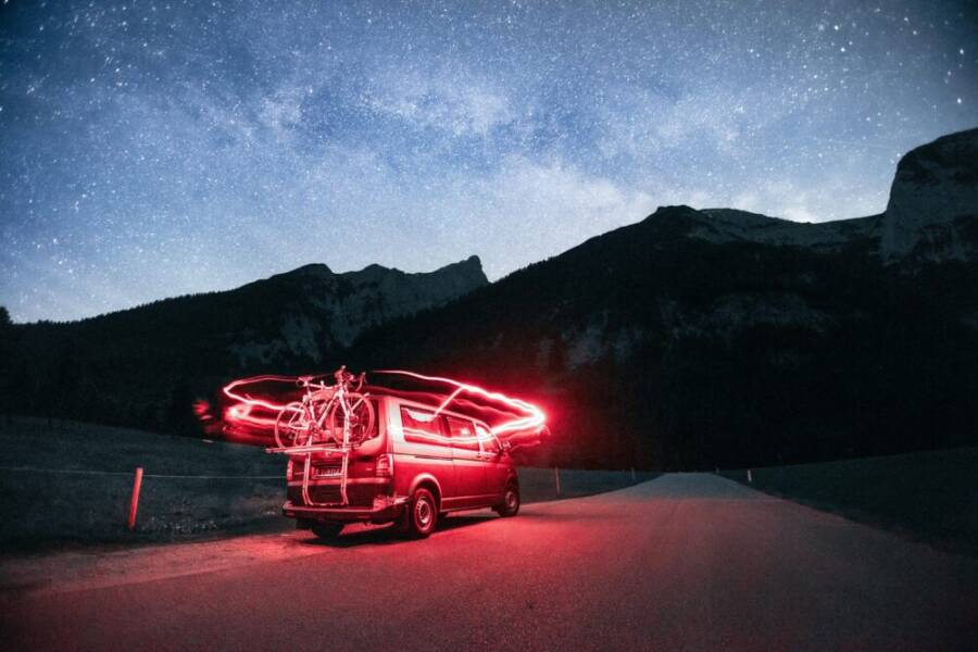 一輛自行車露營車在山地風景中佈滿星星的迷人夜空。