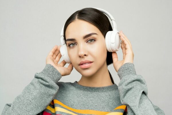 黃色白色拿著耳機灰色和毛衣的女人