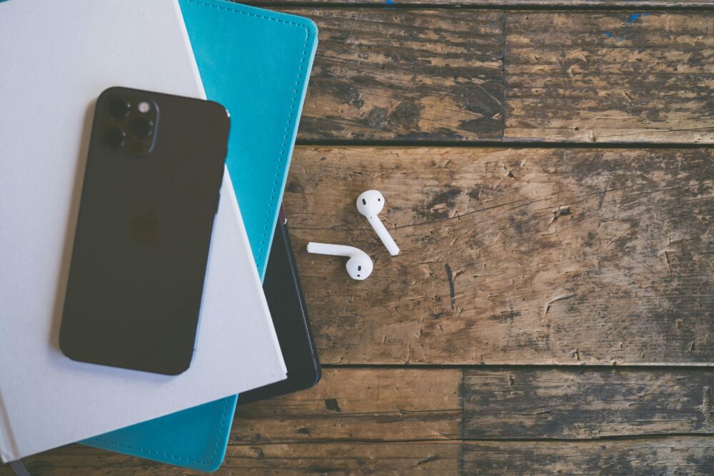 Close-up of phone and wireless earbuds on wooden surface, highlighting modern technology.