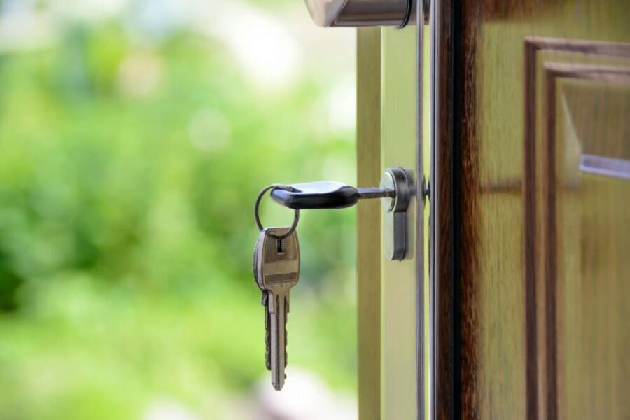 Key inserted in door lock against a blurred green background