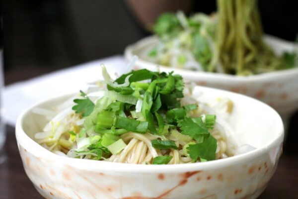 Delicious bowl of Taiwanese noodles topped with fresh herbs and greens.