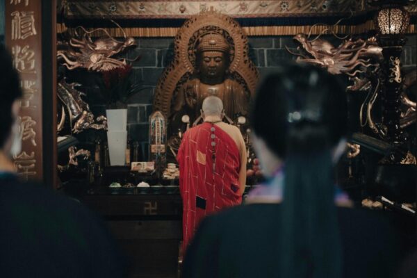 Monk in robe praying before a Buddha statue in a temple in Xinyi District, Taipei.