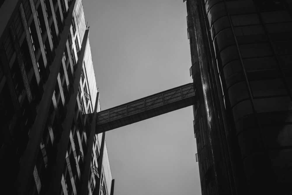 Monochrome view of towering skyscrapers connected by a skybridge