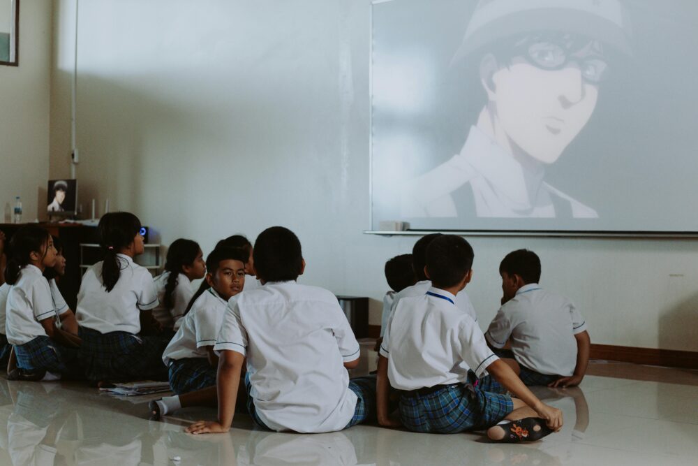 Young students in uniforms watch an educational video in a classroom setting