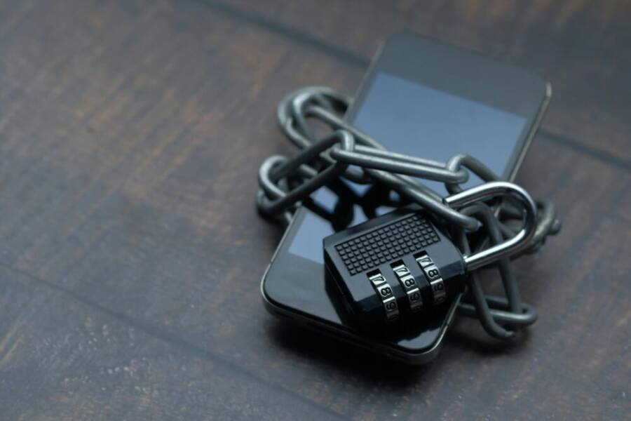Close-up of a smartphone wrapped in a chain with a padlock, symbolizing strong security.