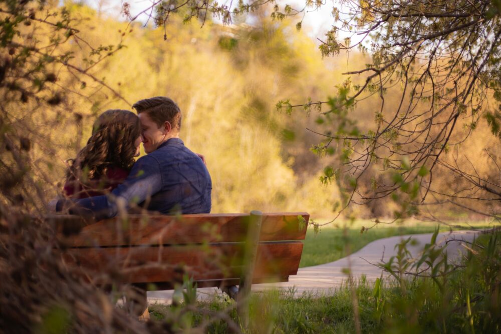A couple enjoying a cozy moment on a park bench surrounded by nature