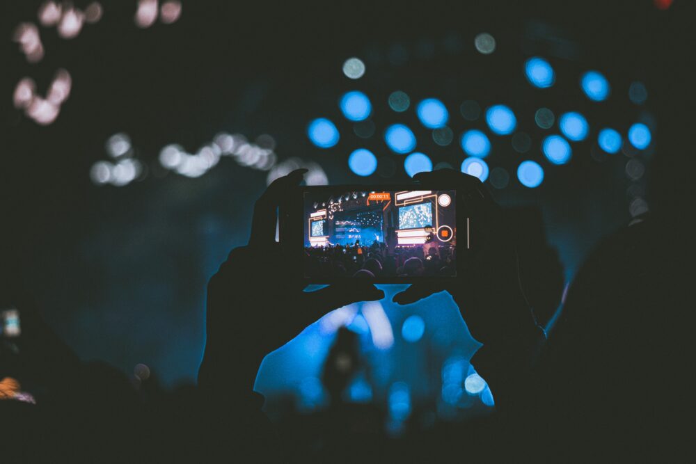 A vibrant concert scene captured through a smartphone, showcasing lively bokeh lights
