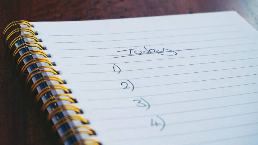 A close-up view of a handwritten to-do list on a spiral notebook with numbers for tasks