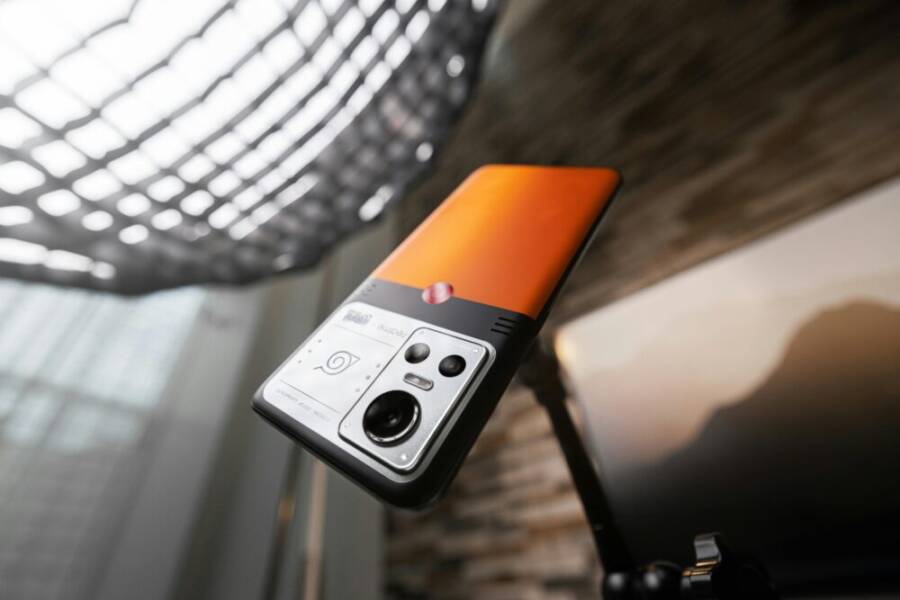Sleek orange smartphone mounted on a tripod, showcasing advanced camera features.