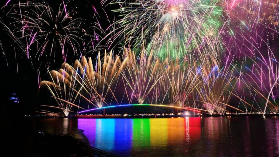 Brilliant fireworks display over the illuminated Rainbow Bridge in Taiwan, reflecting in the water below