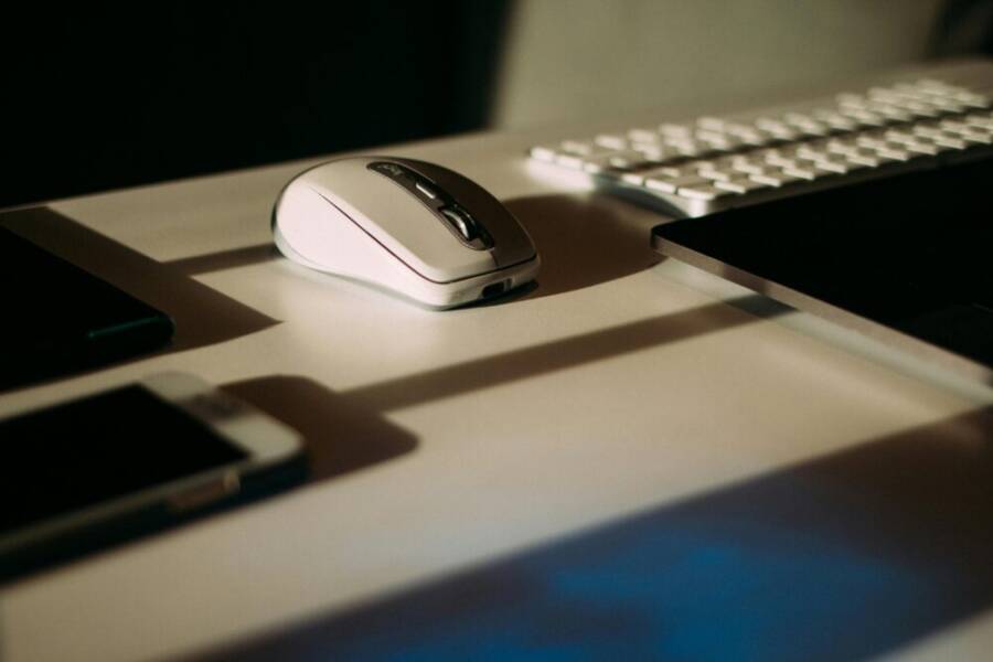 Close-up of a mouse, keyboard, and smartphone in a modern workspace.