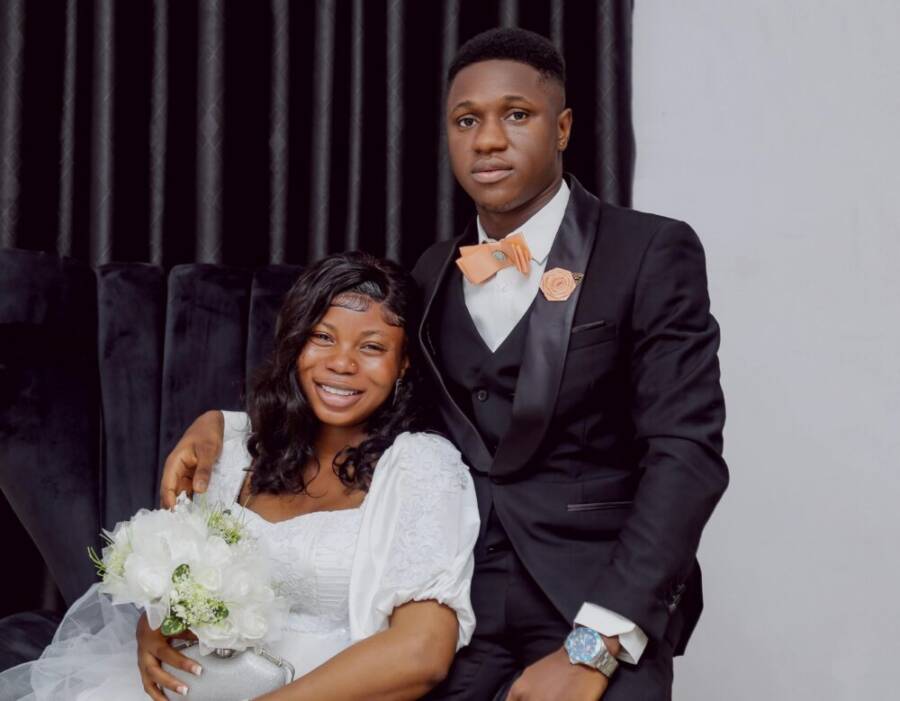 A joyful bride and groom pose indoors, highlighting love and happiness in wedding attire.