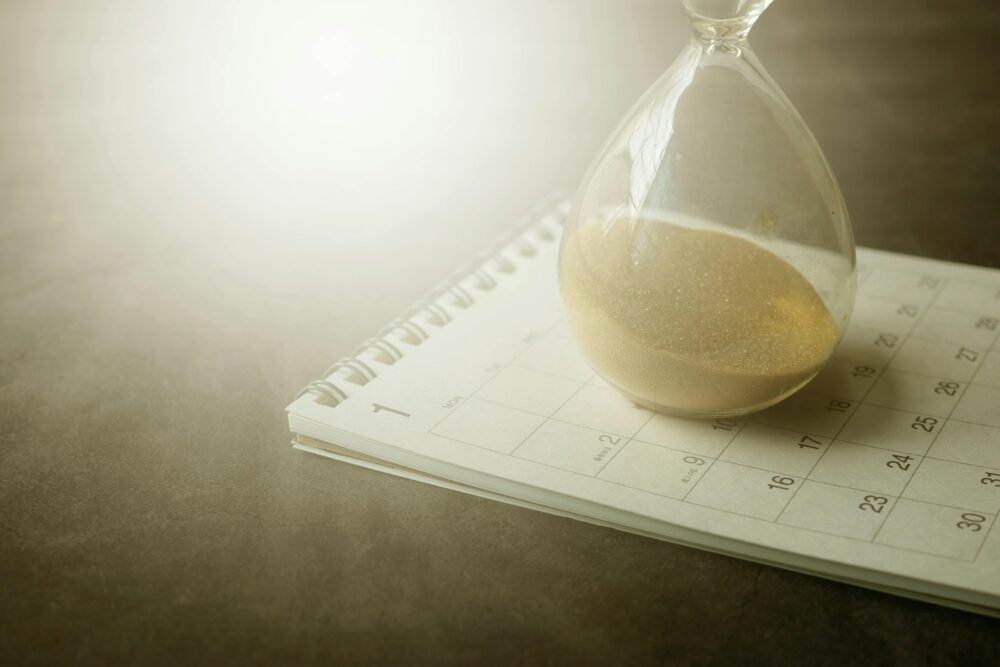 An hourglass on a calendar captures the essence of time management and urgency.