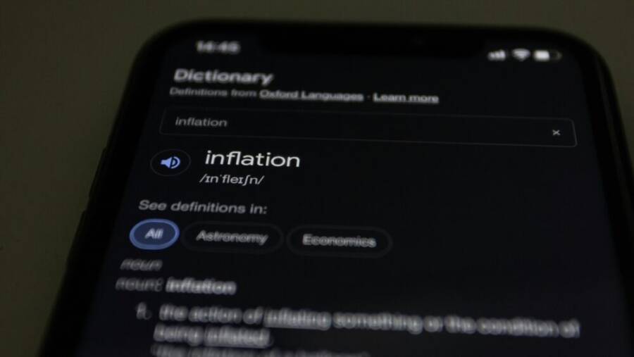Close-up of a smartphone screen showing the word inflation defined in a dictionary app