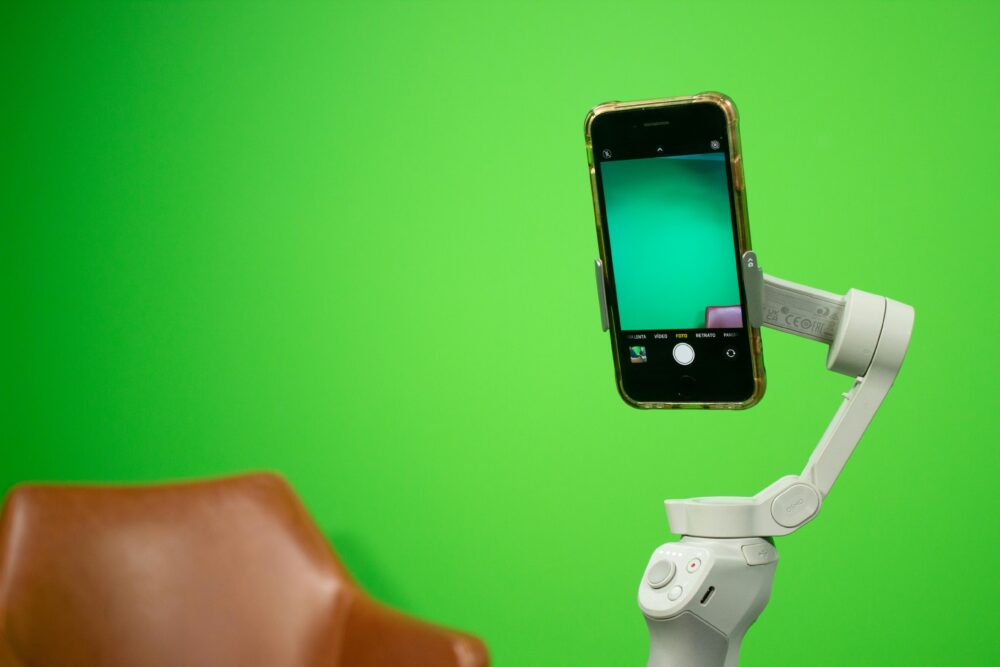 Smartphone mounted on a stabilizer in front of a green screen setup for video production