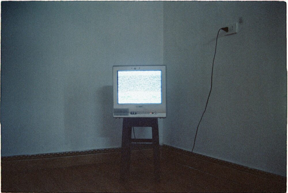 A vintage CRT television displaying static noise in a minimalist room setting