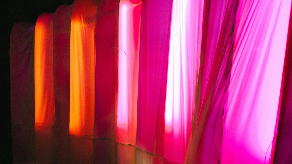 Colorful illuminated curtains in pink and orange tones creating a warm, abstract indoor ambiance
