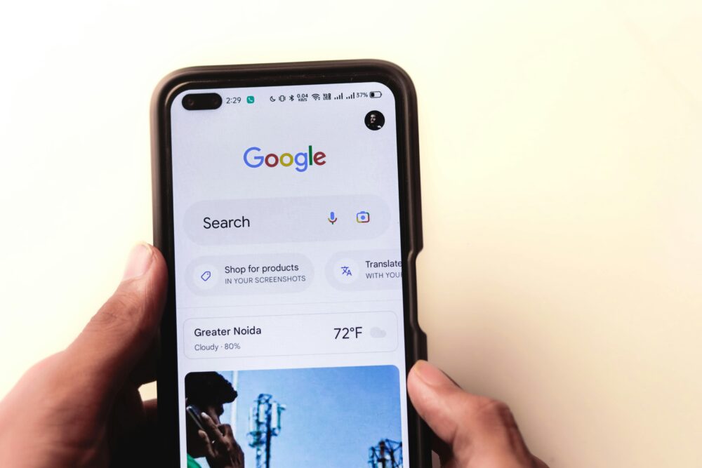 A close-up of a hand holding a smartphone with Google search displayed on the screen