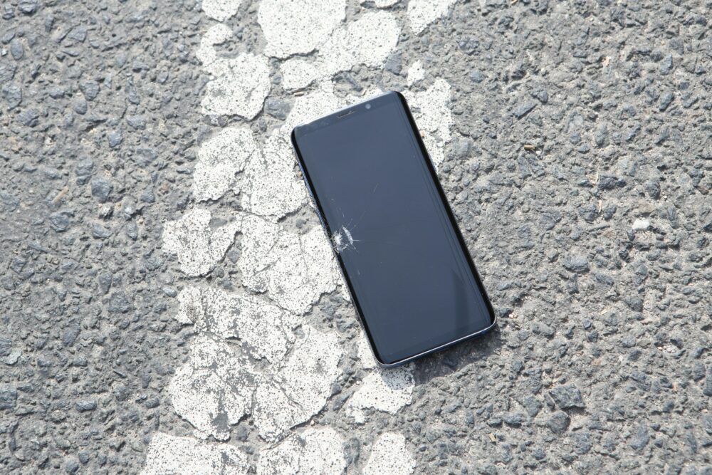 A cracked smartphone lying on a textured surface