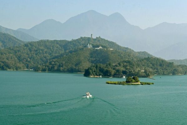 A picturesque aerial view of a boat on Sun Moon Lake surrounded by lush hills in Taiwan.