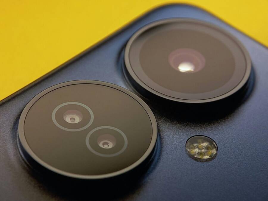 Extreme close-up of smartphone camera lenses with vibrant yellow background, showcasing modern technology.