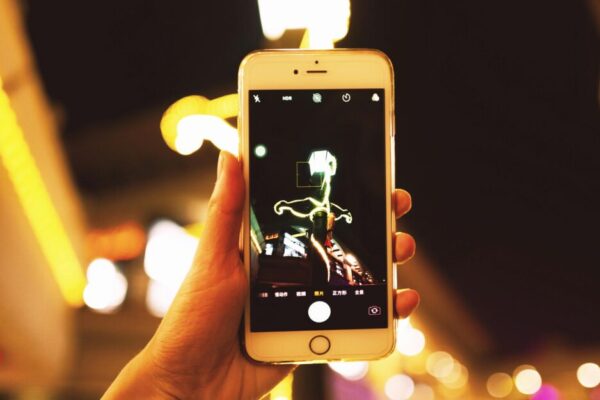 Hand holding smartphone capturing city lights at night