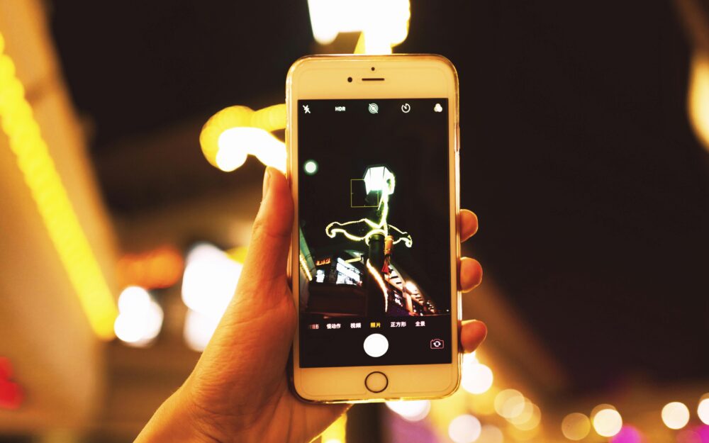 Hand holding smartphone capturing city lights at night