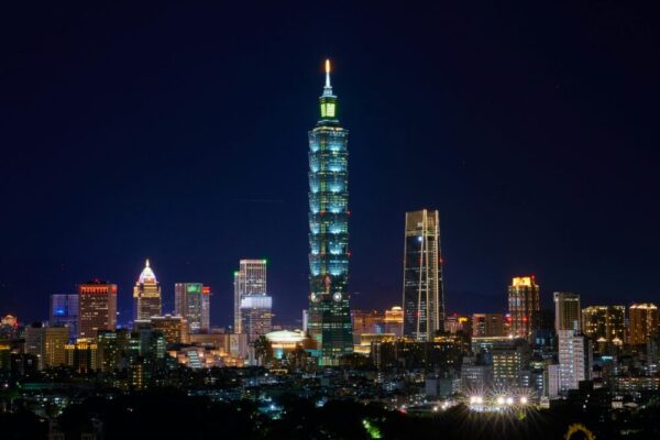 Illuminated Taipei 101 and city skyline at night showcasing modern urban architecture.