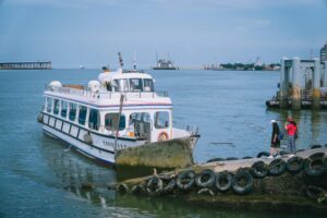 A ferry docked at a shore in New Taipei City, Taiwan, with people strolling by the sea.