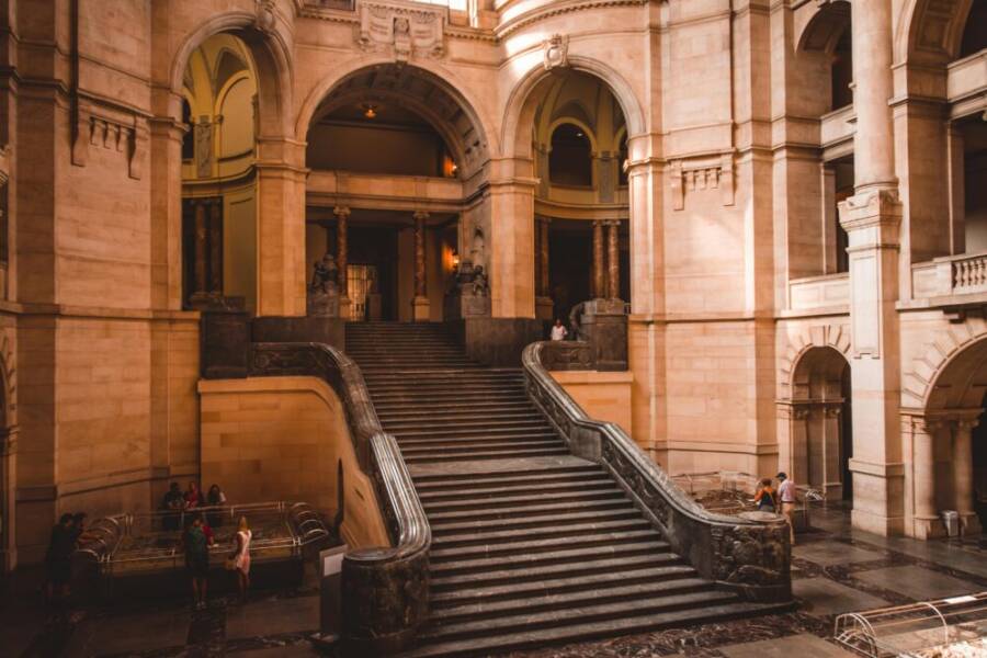 Elegant staircase in a historic building with ornate architecture and people exploring.