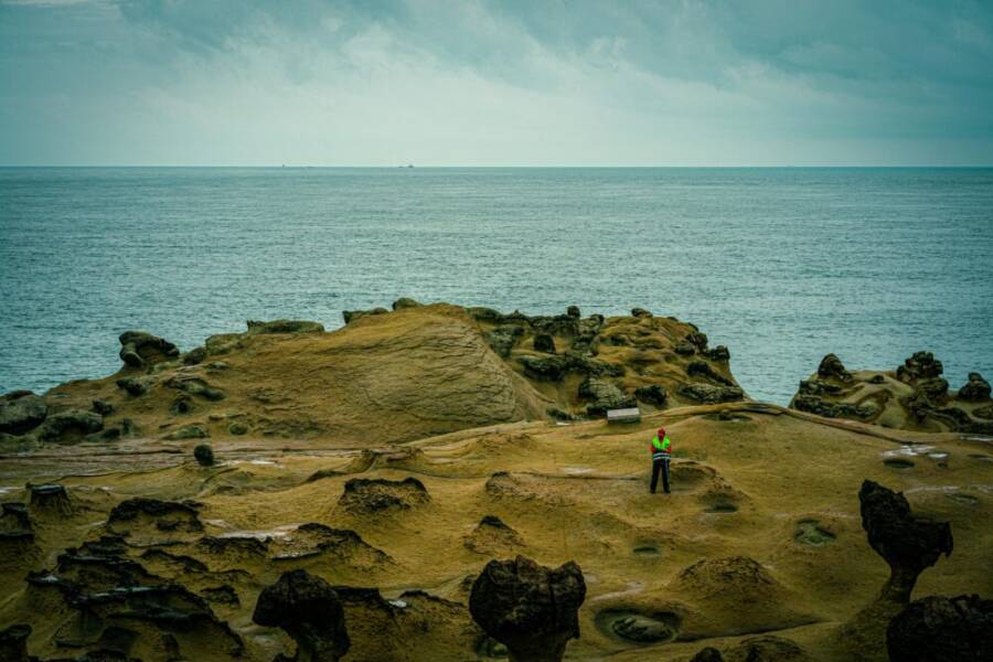 Explore the unique rock formations at Yehliu Geopark by the sea, featuring a lone person admiring the scenery.