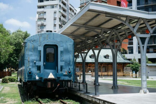 Vintage blue train at historic Taipei railway station platform under blue sky