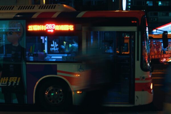 Blurred evening scene of a lit bus in Taipei, showcasing urban hustle and transportation.