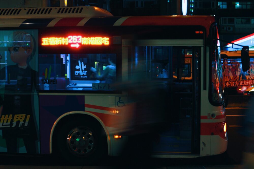 Blurred evening scene of a lit bus in Taipei, showcasing urban hustle and transportation.