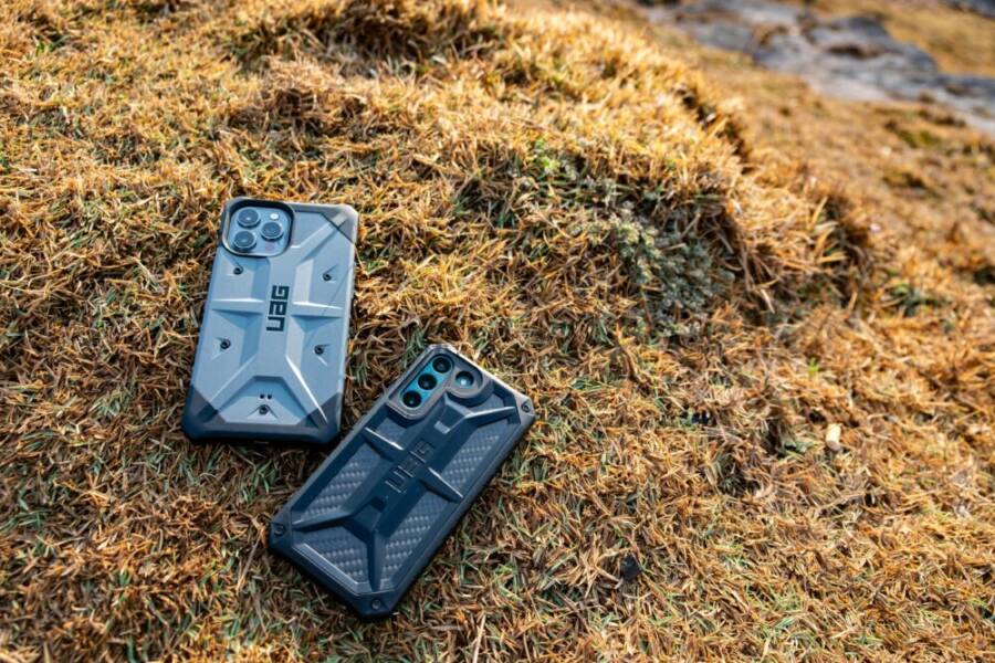 Two rugged smartphones with protective cases on dried grass, Phan Thiet, Vietnam.