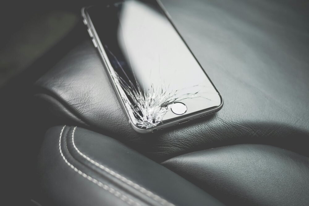 Close-up of a broken smartphone on a leather car seat