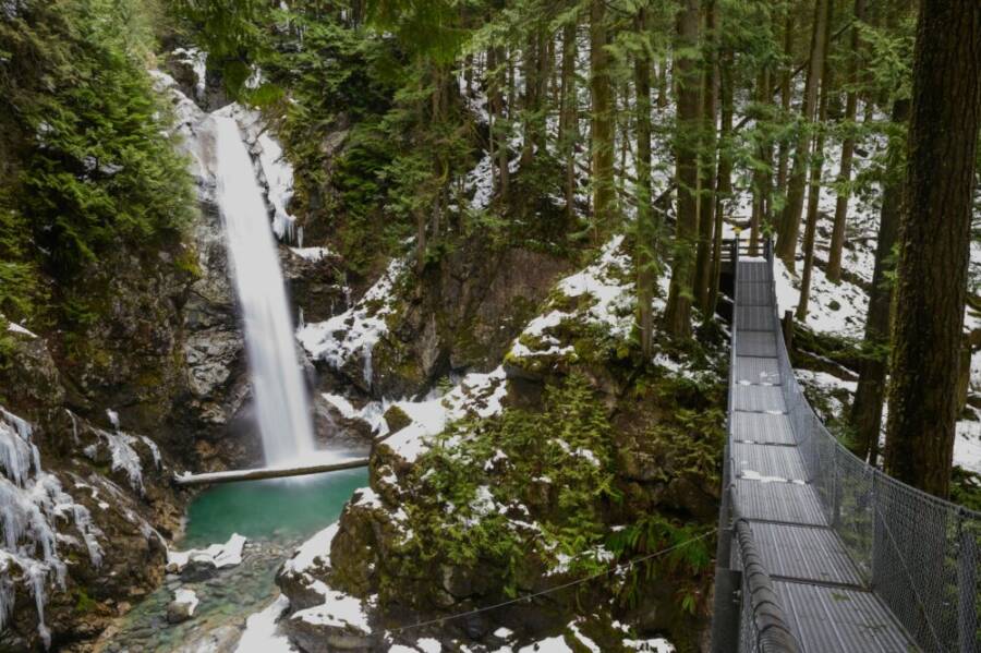 Snowy waterfall with suspension bridge in lush Mission forest