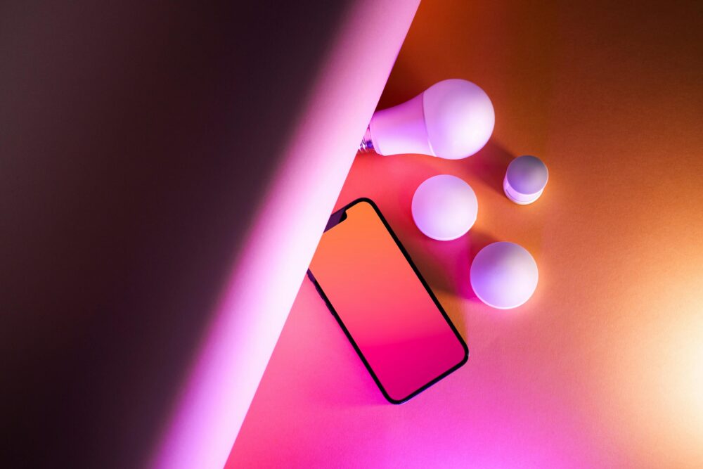 Vibrant artistic composition of smart home bulbs and smartphone on a gradient background