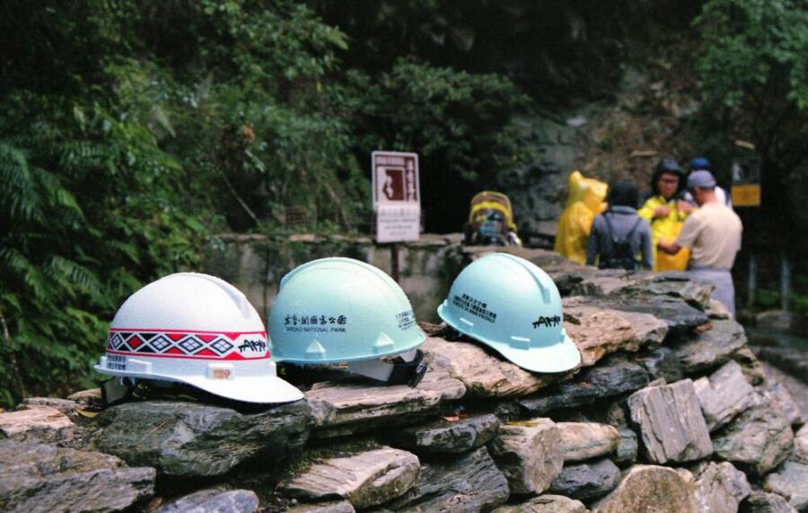 Safety helmets on a stone wall at Taroko National Park, Taiwan, with hikers in the background.