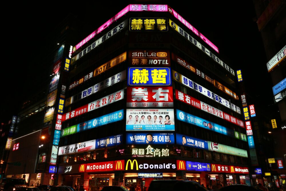 Illuminated building in Taipei showcasing vibrant nightlife and diverse advertising signs on a bustling street.