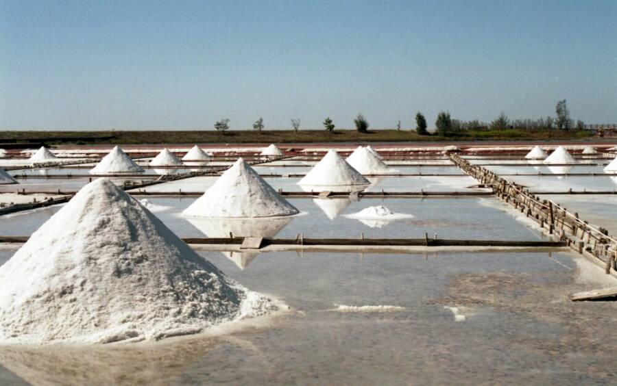 image: Scenic view of traditional salt fields with salt mounds under a clear sky in Tainan, Taiwan.