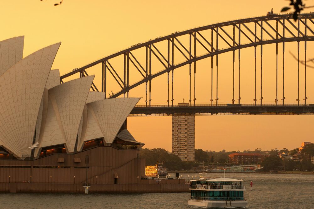 Iconic Sydney landmarks, the Opera House and Harbour Bridge, captured at sunset.
