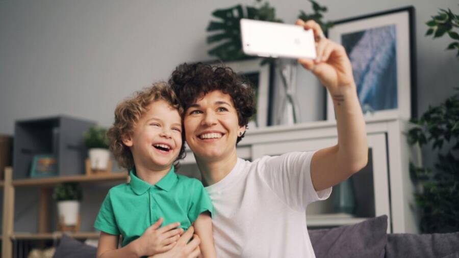 A joyful mother and son duo taking a selfie indoors, capturing a happy moment