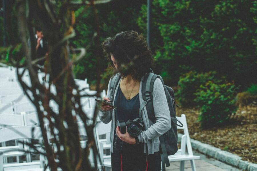 Woman photographer with camera and cellphone among chairs in an outdoor setting