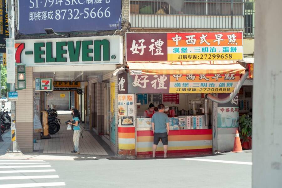 Urban street scene featuring a 7-Eleven and food stalls in Taipei, Taiwan, capturing local shopping culture.