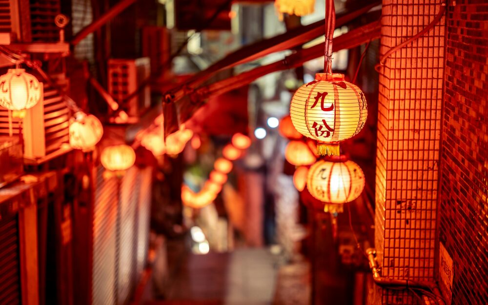 Vibrant night scene of a narrow street in Taipei adorned with glowing red lanterns, creating a warm atmosphere.